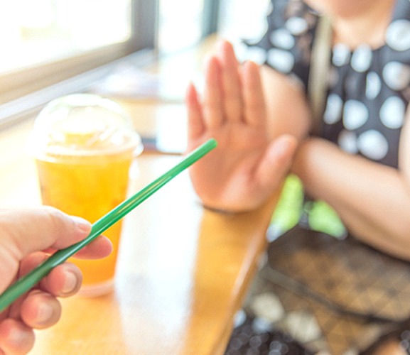 Person handing another person a straw for a beverage