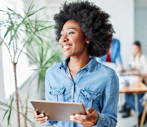 Woman smiling while holding tablet in office