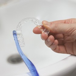 Patient using toothbrush to clean aligner