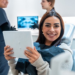 Woman smiling while holding mirror in treatment chair