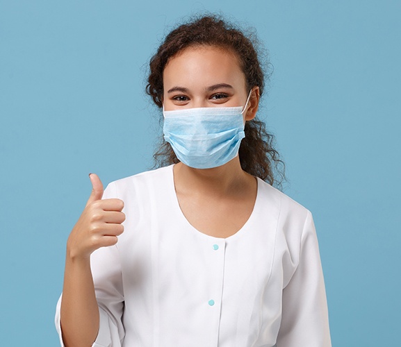 Woman in face mask giving thumbs up