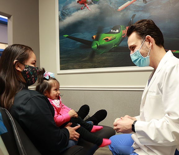 Mother and infant child in dental chair talking to dentist