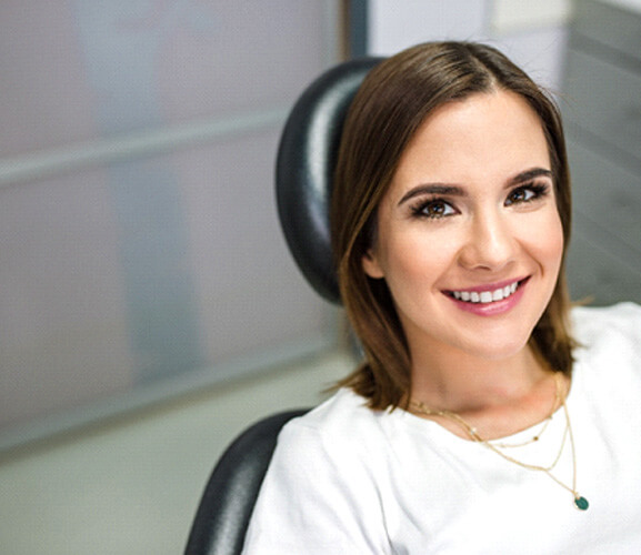 a smiling young woman sitting in a dentists chair
