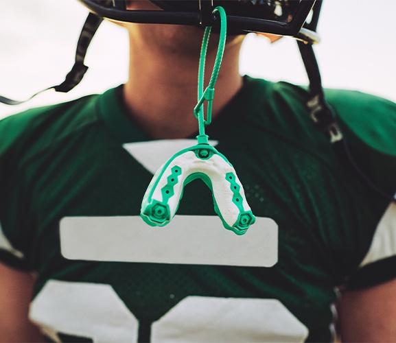 Green athletic mouthguard hanging from football helmet