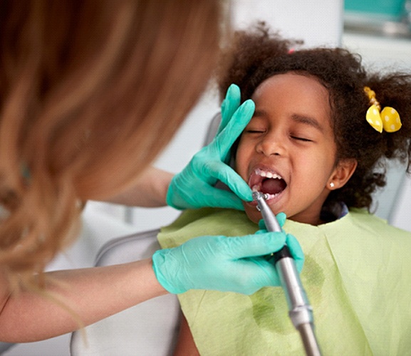 A Medicaid dentist in Dallas cleaning a little girl’s teeth during a normal checkup and cleaning appointment