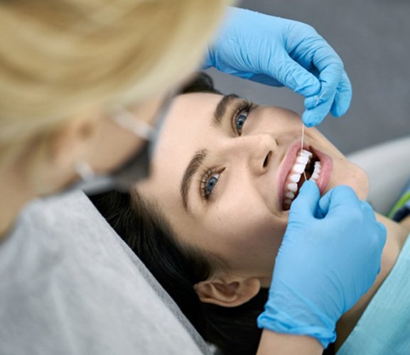 flossing patient’s teeth during dental exam in Dallas   
