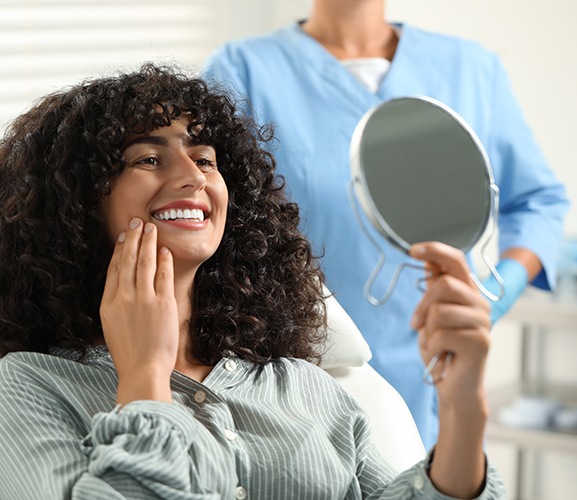 a patient admiring her smile in a handheld mirror