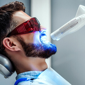 man havign teeth whitening in dental chair