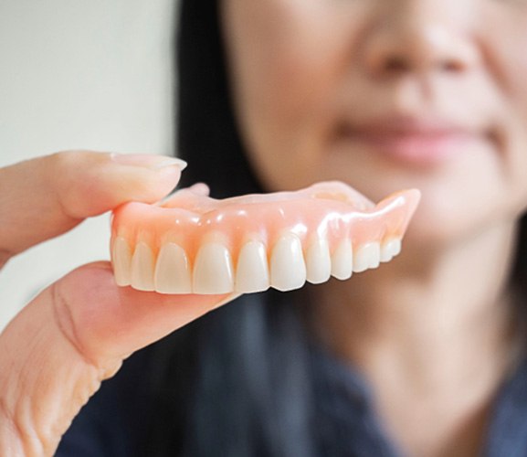 Woman holding full denture