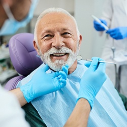 An elderly man getting dentures from a dentist 