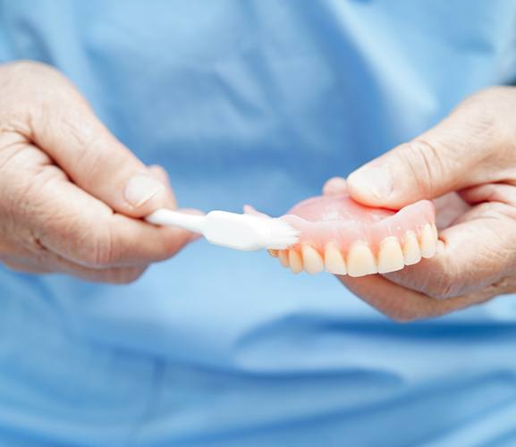 A dentist illustrating how to care for dentures