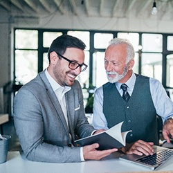 A senior businessperson working with a colleague