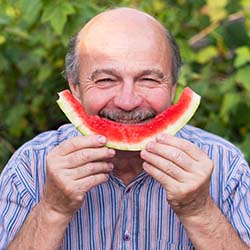 Man eating watermelon to prevent dental emergencies in Dallas