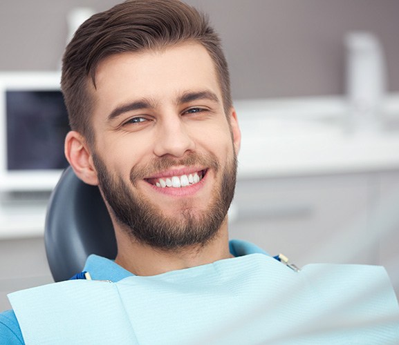 A smiling, bearded man sitting in a dentist’s chair