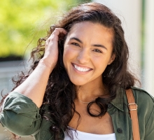 Young woman with curly hair smiling outdoors