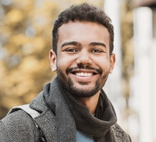 Young man with scarf smiling outdoors