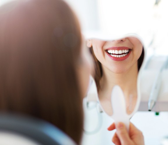 Woman looking at her flawless smile in mirror