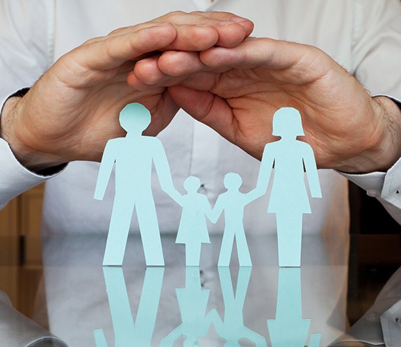 Hands covering paper cut out family