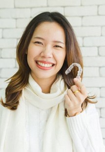 a woman near Farmer’s Branch holding Invisalign trays 