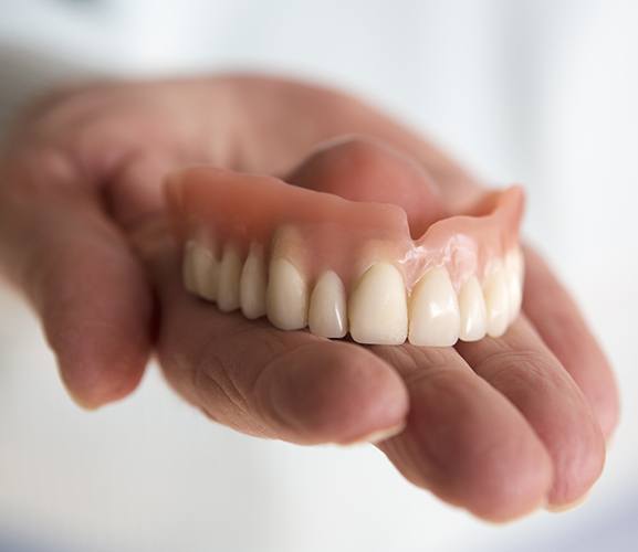 Hand holding a denture