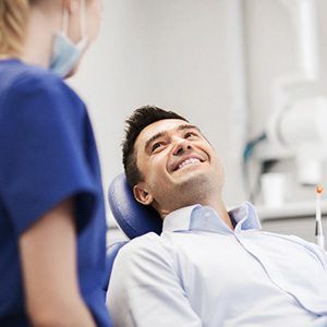 Male patient smiling while talking to dental assistant
