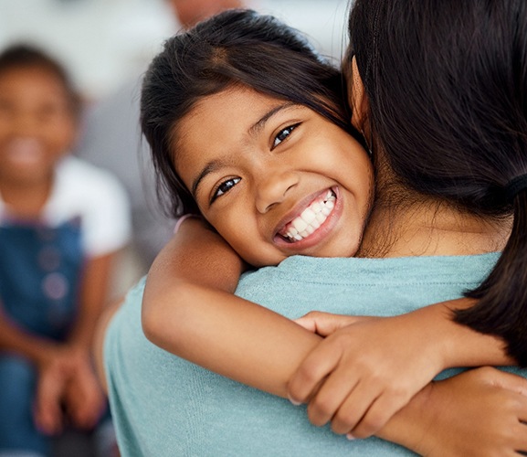 Girl hugging her parent and smiling