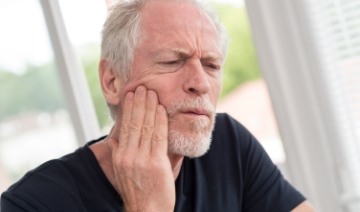 Man in need of emergency dentistry holding his cheek