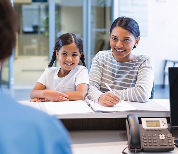 Mother and daughter checking in at dental office reception desk