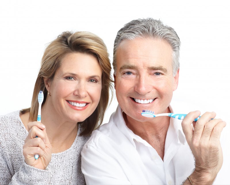 Older couple holding toothbrushes together and smiling