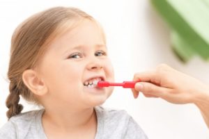 Parent brushing a baby’s teeth