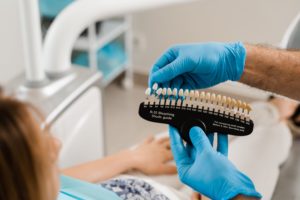 Dentist in blue gloves holding up a shade guide