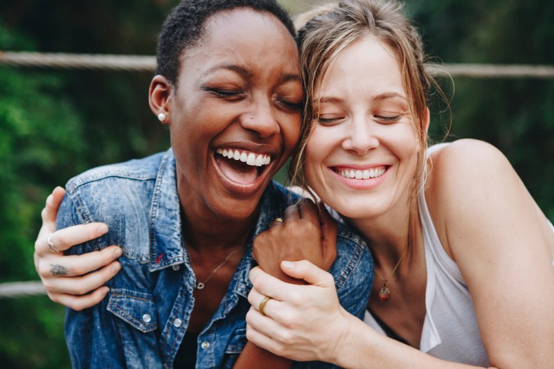 Woman smiling with a friend after being gifted teeth whitening